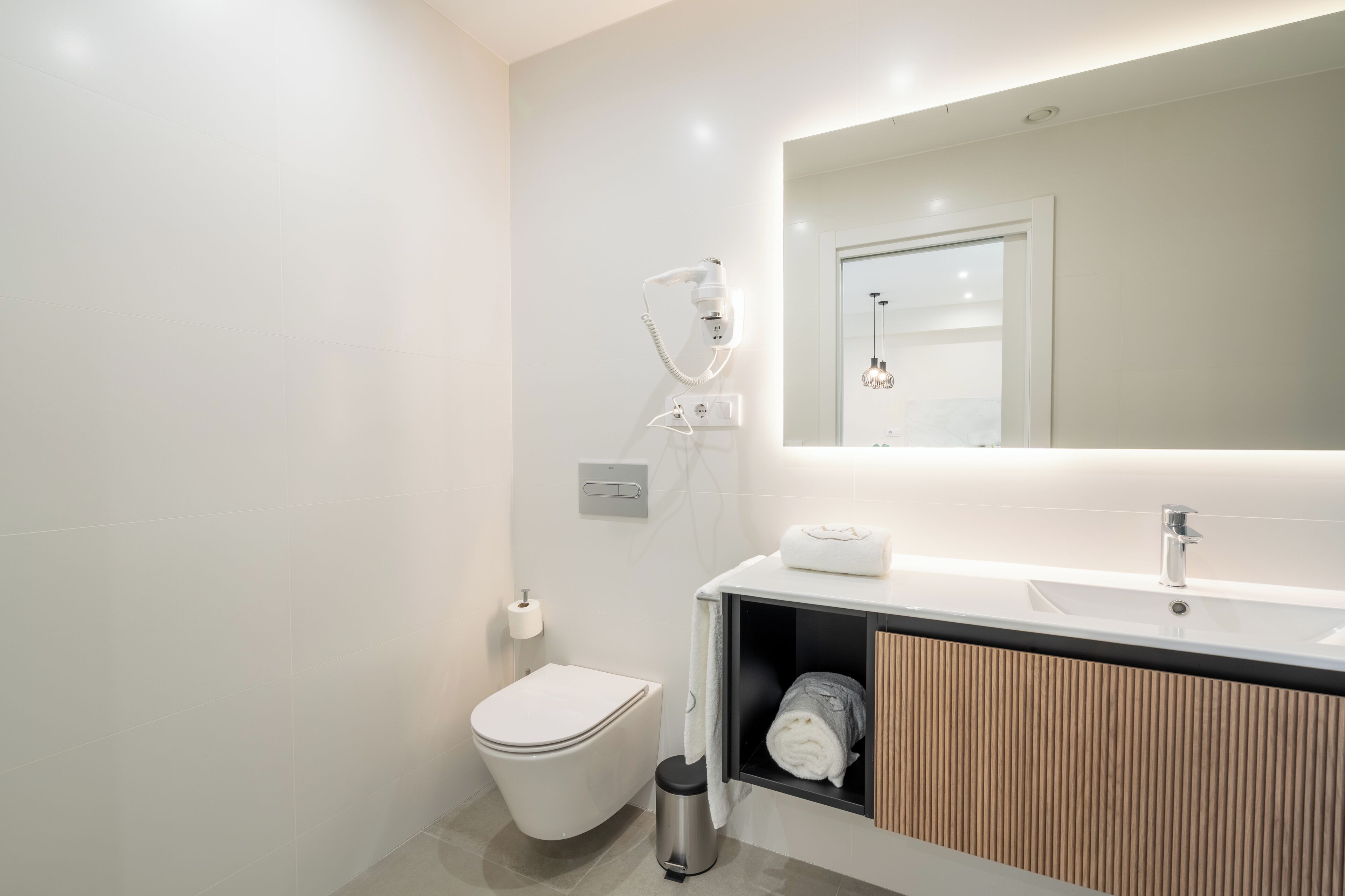 A modern bathroom with a toilet, sink, and mirror.