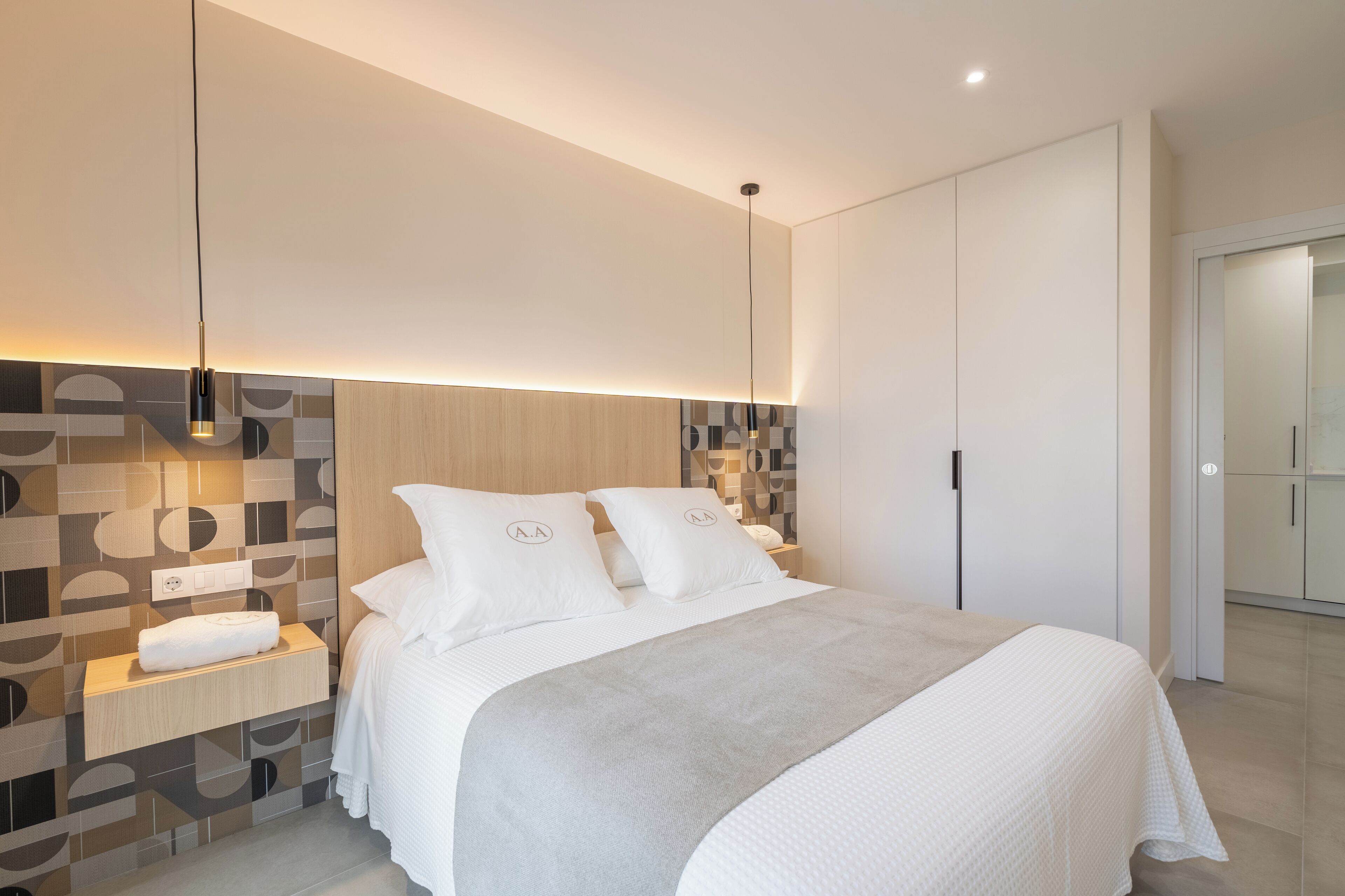 Un dormitorio moderno con una cama grande, una mesita de noche y un aplique de pared.