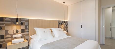 Un dormitorio moderno con una cama grande, una mesita de noche y un aplique de pared.