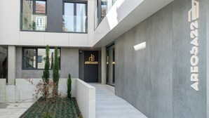 A modern building with a grey facade, a visible entrance, and a sign reading "AREOSA22".