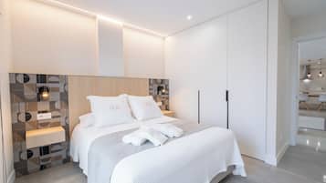 A modern bedroom with a large bed, built-in wardrobe, and a bedside table.