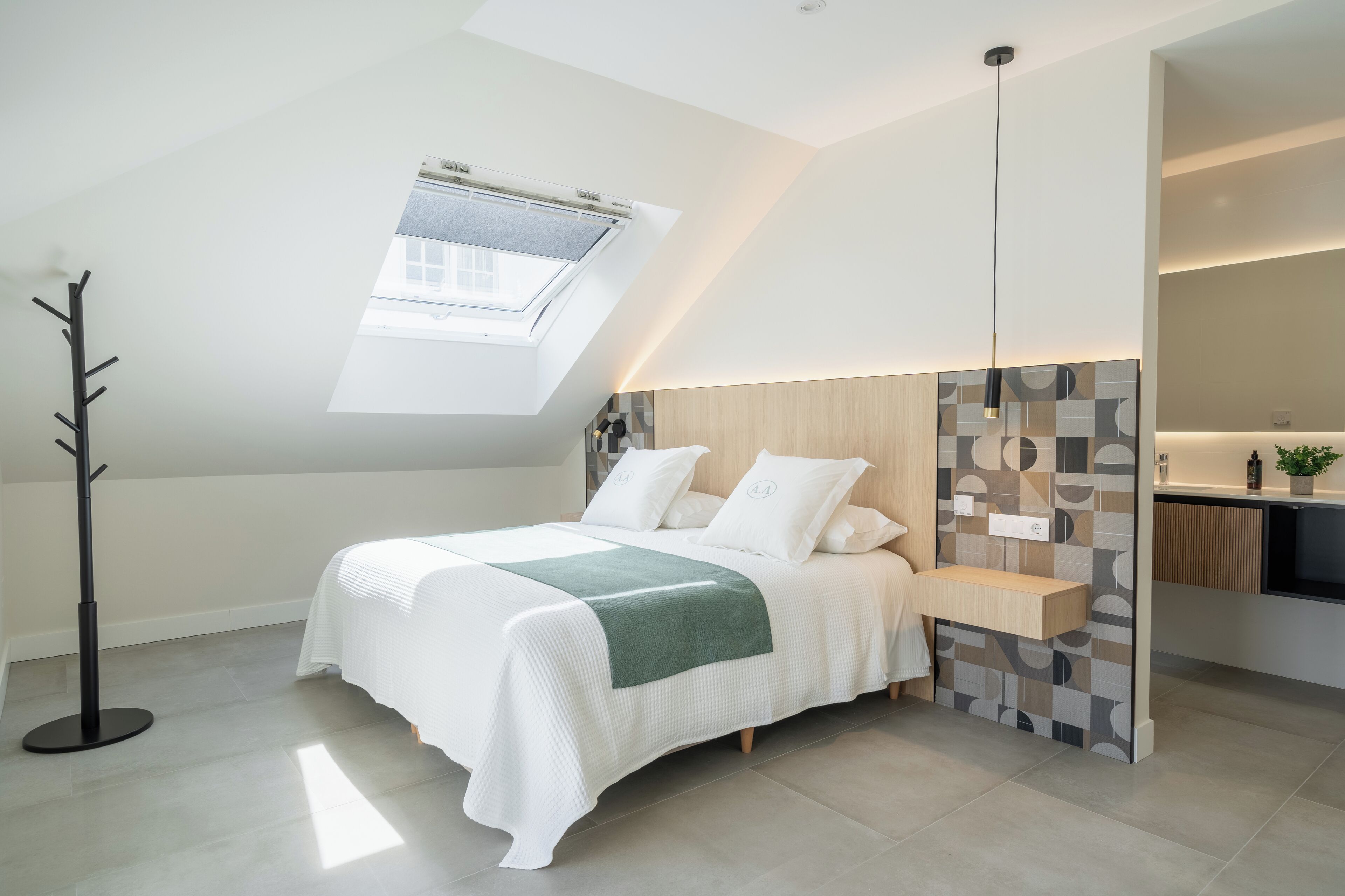 A modern bedroom with a skylight, a bedside table, and a built-in bench.