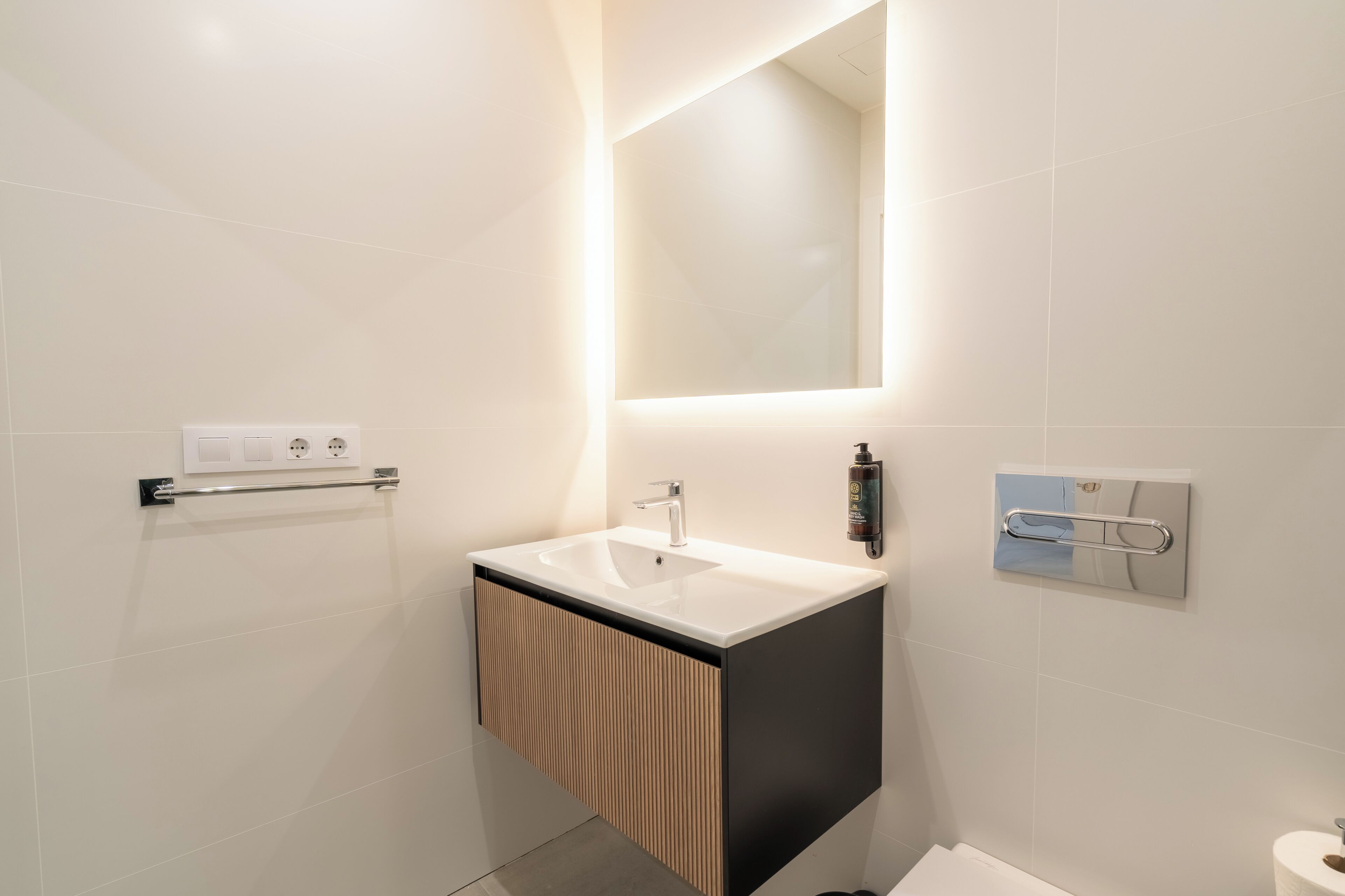 A modern bathroom with a white sink, a mirror, and a towel rack.