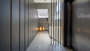 A modern hallway with a skylight, a staircase, and two wicker lamps.
