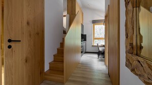 Un escalier en bois mène à un espace cuisine agrémenté d’une fenêtre qui laisse entrer la lumière naturelle.