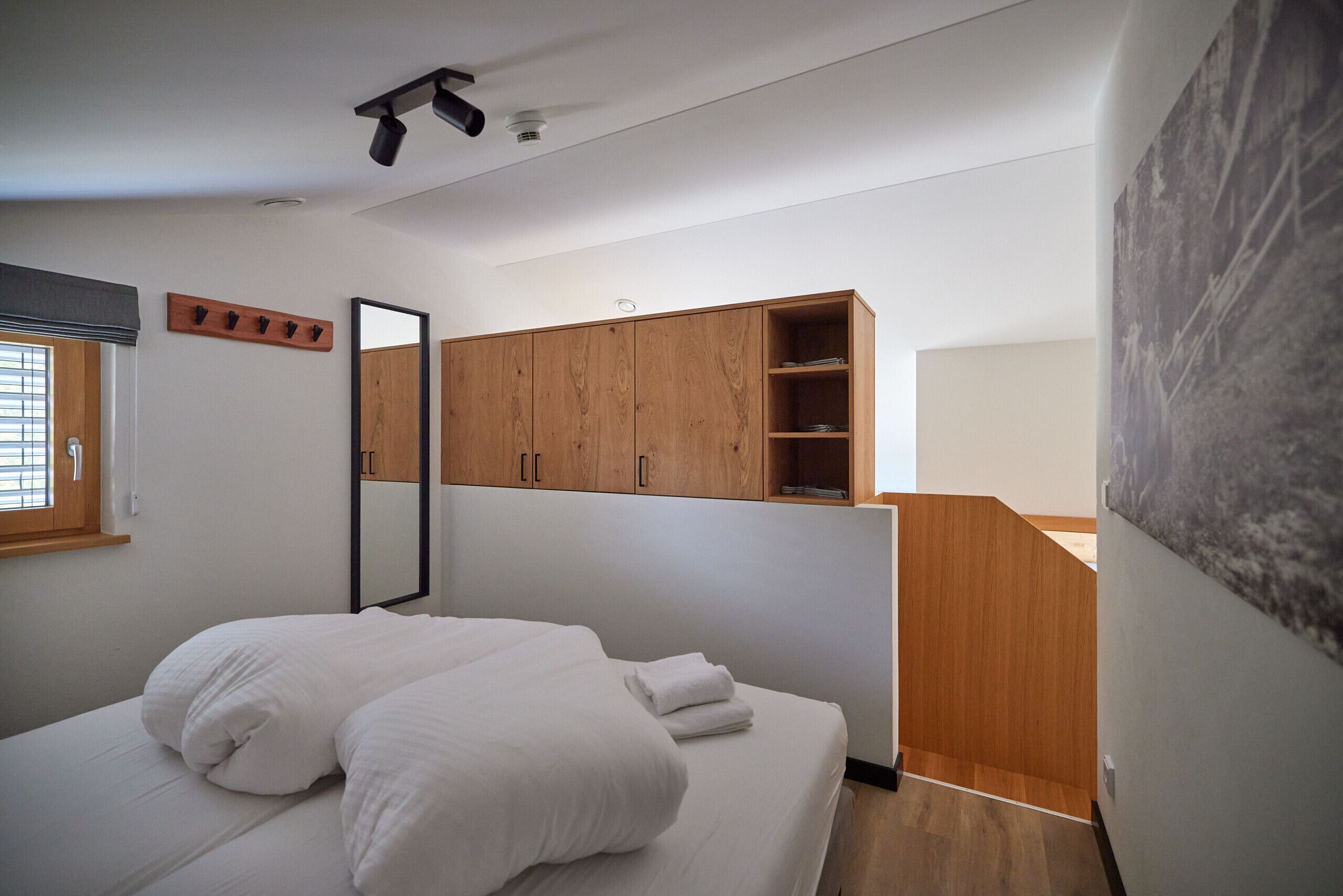 A bedroom with a bed, wooden wardrobe, and a mirror.