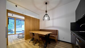 A modern kitchen with a wooden dining table, black chairs, and a hanging light fixture. - 59305 Birkhuhn 305 (Gargellen)