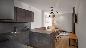 Een moderne keuken met donkere kastjes, een centraal eiland en een eethoek met een houten tafel en stoelen.