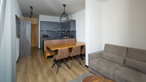 Una cocina moderna con armarios oscuros, una mesa de comedor de madera con sillas y un sofá gris.