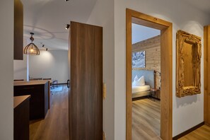 Ein modernes Interieur mit Holzboden, einer Küchenzeile und einem Schlafzimmer mit Bett und Nachttisch.