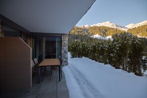 A modern outdoor seating area with a view of snow-covered mountains and pine trees. - 59307 Mauerläufer 307 T S (Gargellen)