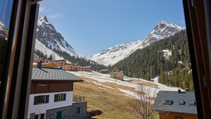 Un pueblo de montaña con picos nevados, casas de madera y un cielo despejado.