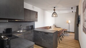 Una cocina moderna con armarios oscuros, una isla integrada y un comedor con suelo de madera y una mesa.
