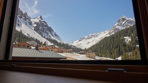 A mountain view with snow-covered peaks and a village with traditional buildings.