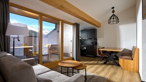 A modern living room with a sofa, a small round table, and a dining area with a wooden bench.