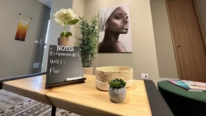 A modern room with a desk, a laptop, a plant, and a welcome sign.