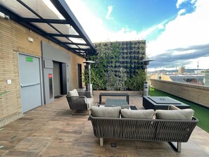 An outdoor seating area with wicker furniture, a green wall with plants, and a view of the city. - Modern brand new apartment (Bogotá)