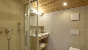 A modern bathroom with a glass-enclosed shower, a wooden vanity, and a toilet.