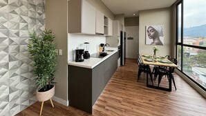 Eine moderne Küche mit einer zentralen Kochinsel, einem Essbereich mit Holztisch und einem großen Fenster mit Blick auf die Stadt.