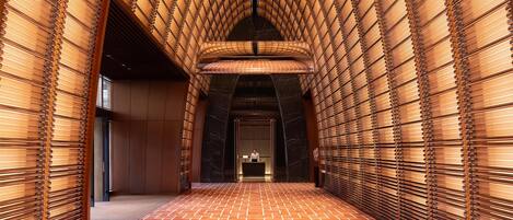 A corridor with a patterned floor and a person standing at a reception desk.