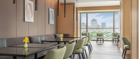 A modern hotel lobby with a long reception desk, seating area, and large windows offering a city view.