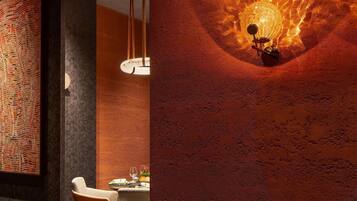 A modern interior with a unique wall feature, a dining area with orange chairs, and a table set for dining.