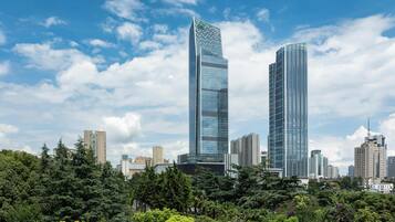 A cityscape with two prominent skyscrapers, surrounded by dense greenery and other buildings.