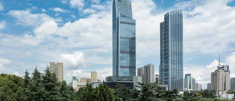 A cityscape with two prominent skyscrapers, surrounded by dense greenery and other buildings.