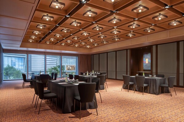 Un salón de conferencias con mesas, sillas y una alfombra estampada.