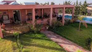 A house with a covered patio, a swimming pool, and a garden with various plants. - L'oliviade Village (Marrakech)