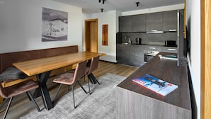 A modern kitchen with dark cabinets, a wooden dining table, and a bench. - 59321 Alpen-Krähe 321 (Gargellen)