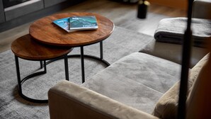 A modern living room with a grey sofa, a round wooden coffee table, and a magazine on the table. - 59315 Steinadler 315 T S (Gargellen)