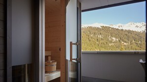 A wooden interior with a glass door leading to a balcony with a mountain view.