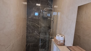 Une salle de bain moderne avec une douche à parois de verre, des toilettes et un meuble-lavabo avec un miroir.