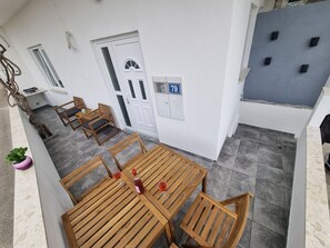 Ein Holz-Tisch mit Stühlen auf einem Balkon, mit einer weißen Tür und einem Schild mit der Nummer 79.