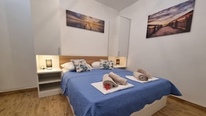Une chambre à coucher avec un lit, des oreillers, une table de chevet, une lampe et des œuvres d’art accrochées aux murs.