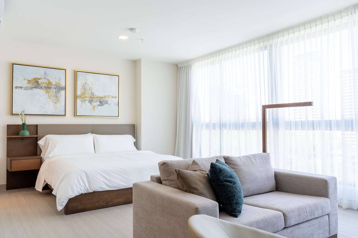 Een moderne hotelkamer met een bed, een bank en twee ingelijste kunstwerken aan de muur.