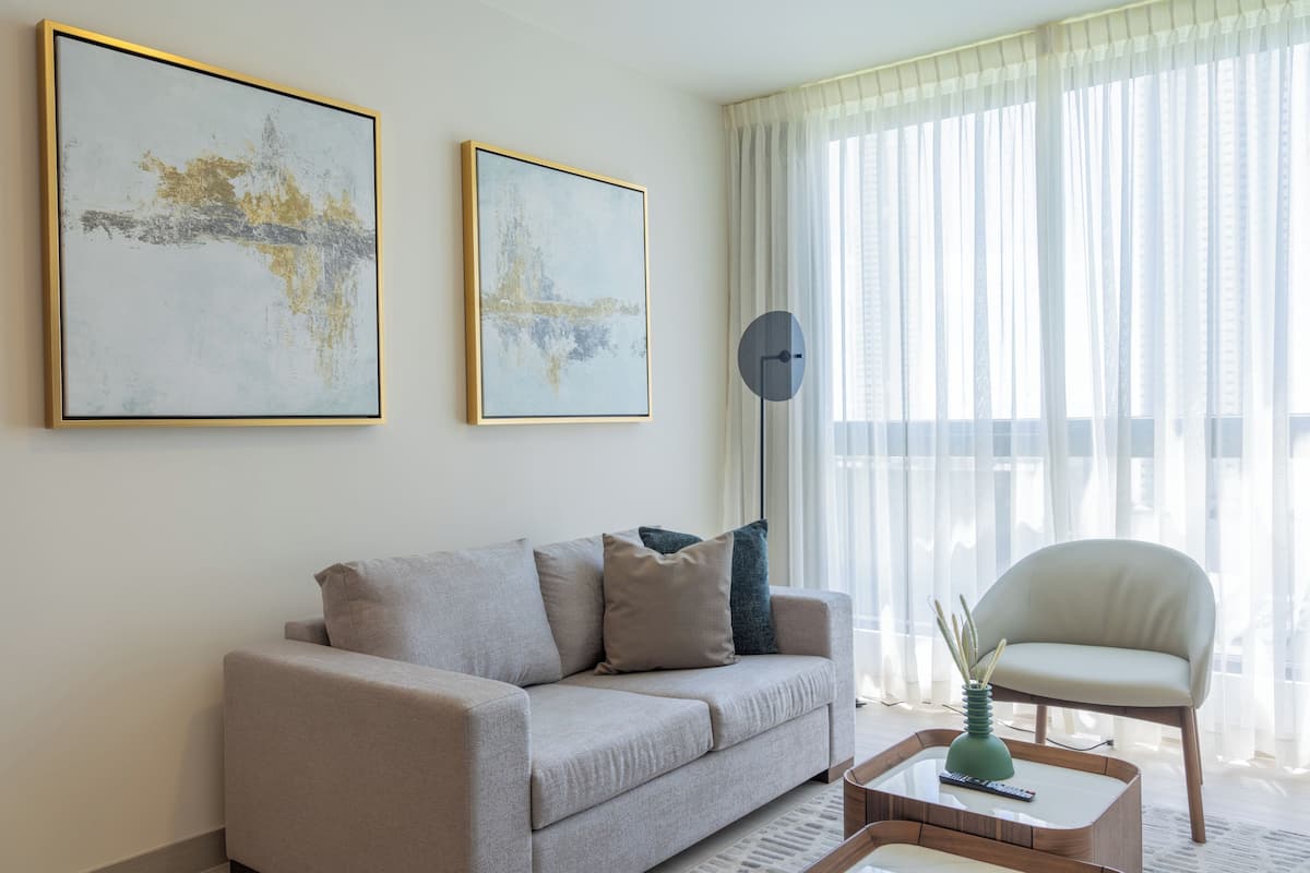 Een moderne woonkamer met een bank, een fauteuil, een salontafel en twee abstracte schilderijen aan de muur.