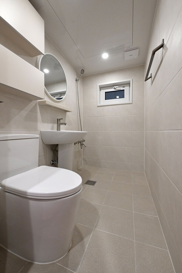 A modern bathroom with a toilet, sink, and shower.