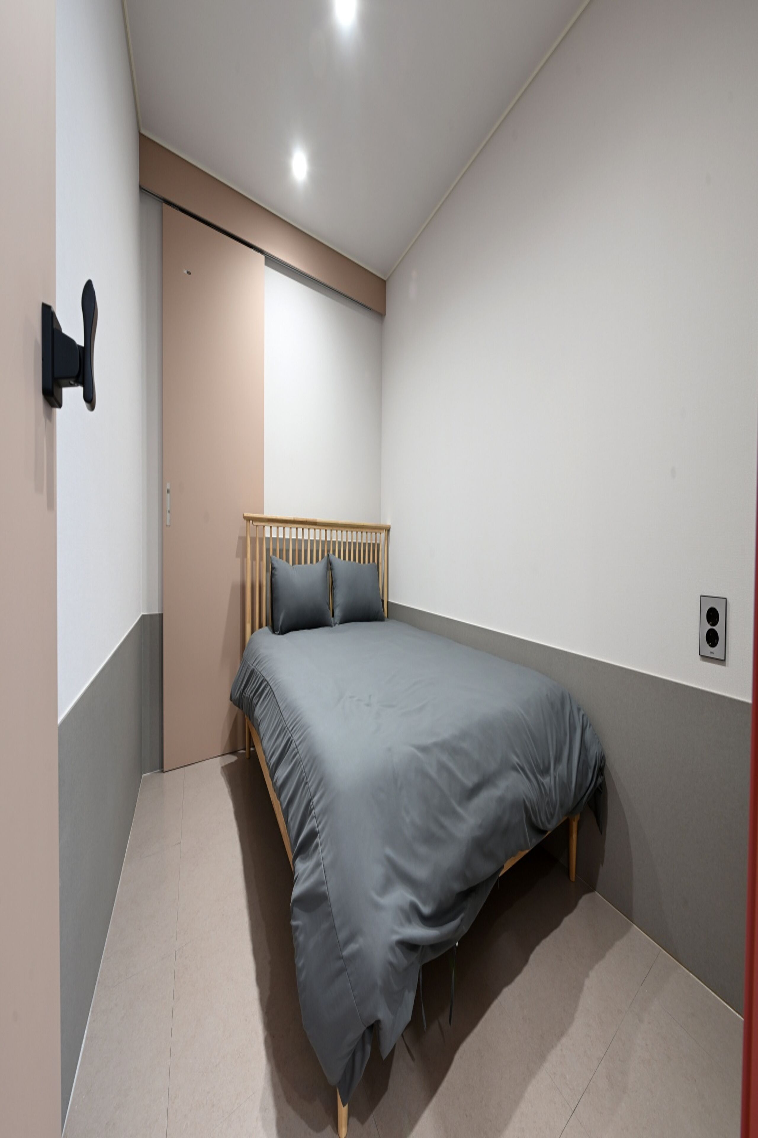 A bedroom with a bed, a door, and a light switch on the wall.