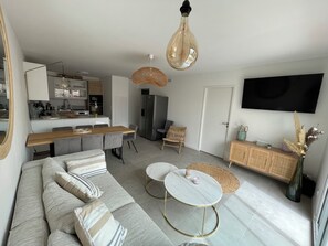 A modern living room with a sofa, coffee table, and dining area. - Magnifique Appartement Neuf, 3 ch 6 p Centre Ville Avec Jardin Calme et Lumineux (Sainte-Maxime)