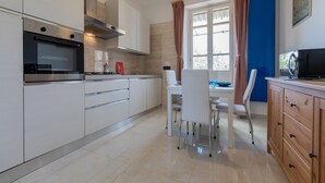 A modern kitchen with stainless steel appliances, white cabinetry, and a dining area with a table and chairs. - The Turin Nest by Wonderful Italy (Turin)