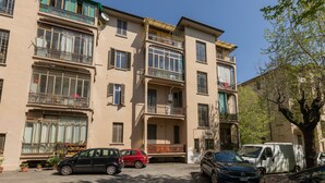 A multi-story building with balconies, parked cars, and potted plants. - The Turin Nest by Wonderful Italy (Turin)