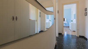 A hallway with a mirrored wall, a white wardrobe, and a glimpse of a kitchen area in the distance. - The Turin Nest by Wonderful Italy (Turin)