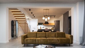 Un salon moderne avec un canapé, une table basse et un escalier menant à un niveau supérieur.