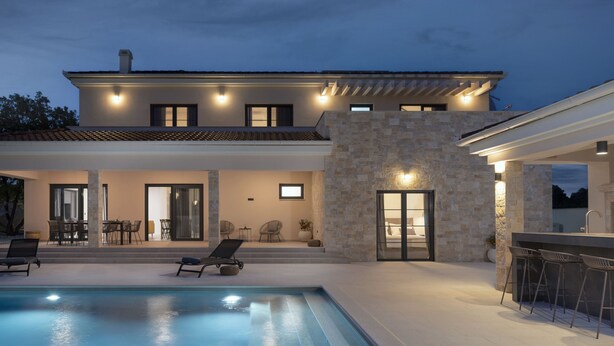 Une maison moderne dotée d’une piscine, d’un espace extérieur aménagé et d’un bar.