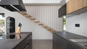 Une cuisine moderne avec un escalier en bois, des appareils électroménagers intégrés et un plan de travail au design épuré.