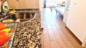 A kitchen with a stainless steel sink, a granite countertop, and a patterned mat. - OLYMPIA STUDIO OCEAN VIEW (Playa de las Américas)