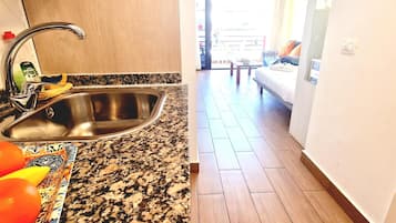 A kitchen with a stainless steel sink, a granite countertop, and a patterned mat.