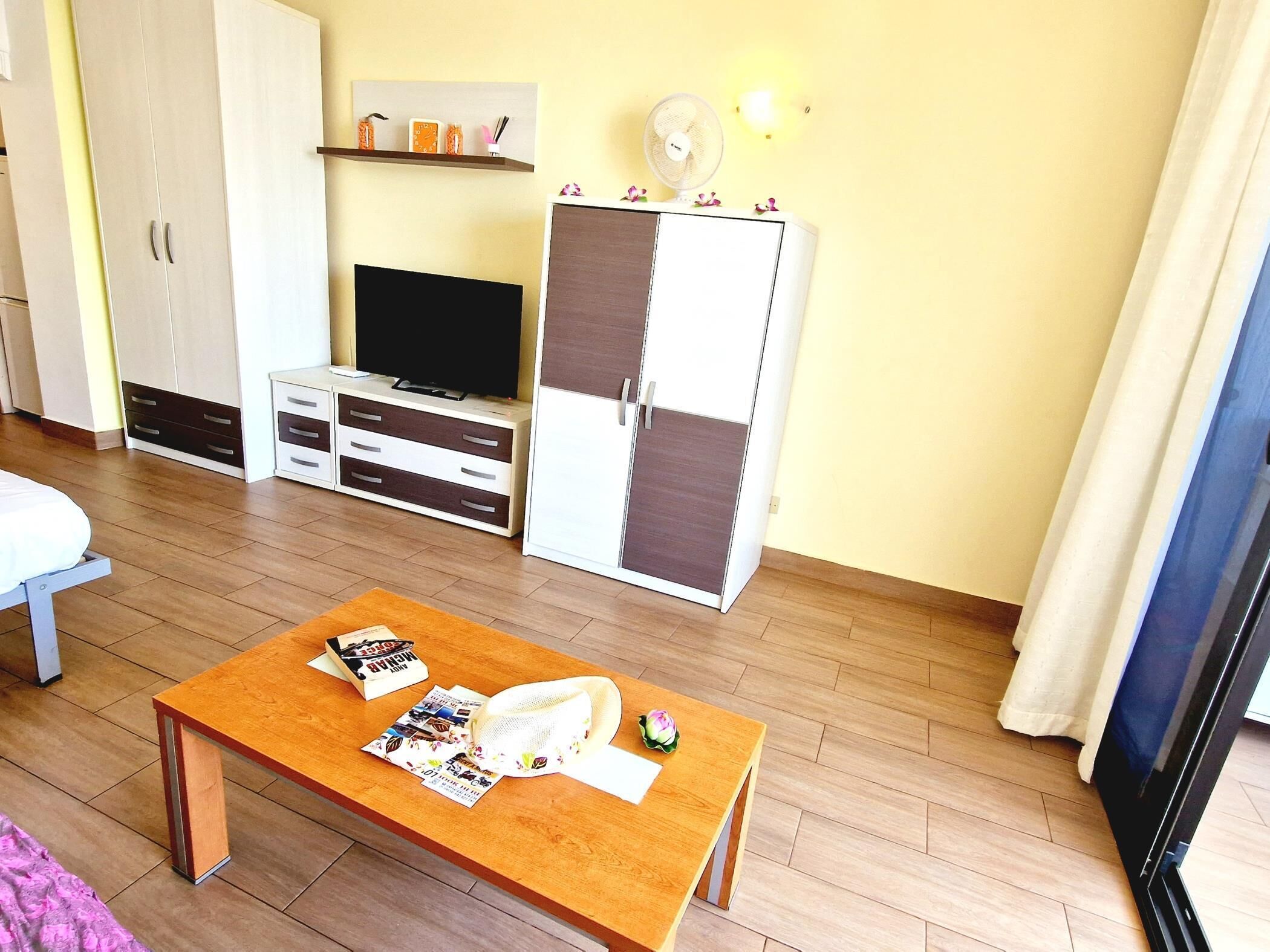 Une pièce avec une table en bois, un téléviseur, une armoire et un lit.